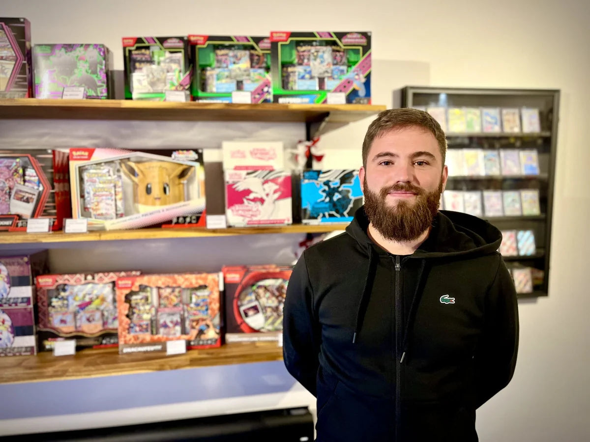 Anthony, founder of Cards Game Collect, in front of the shop's shelves of Pokémon boxes