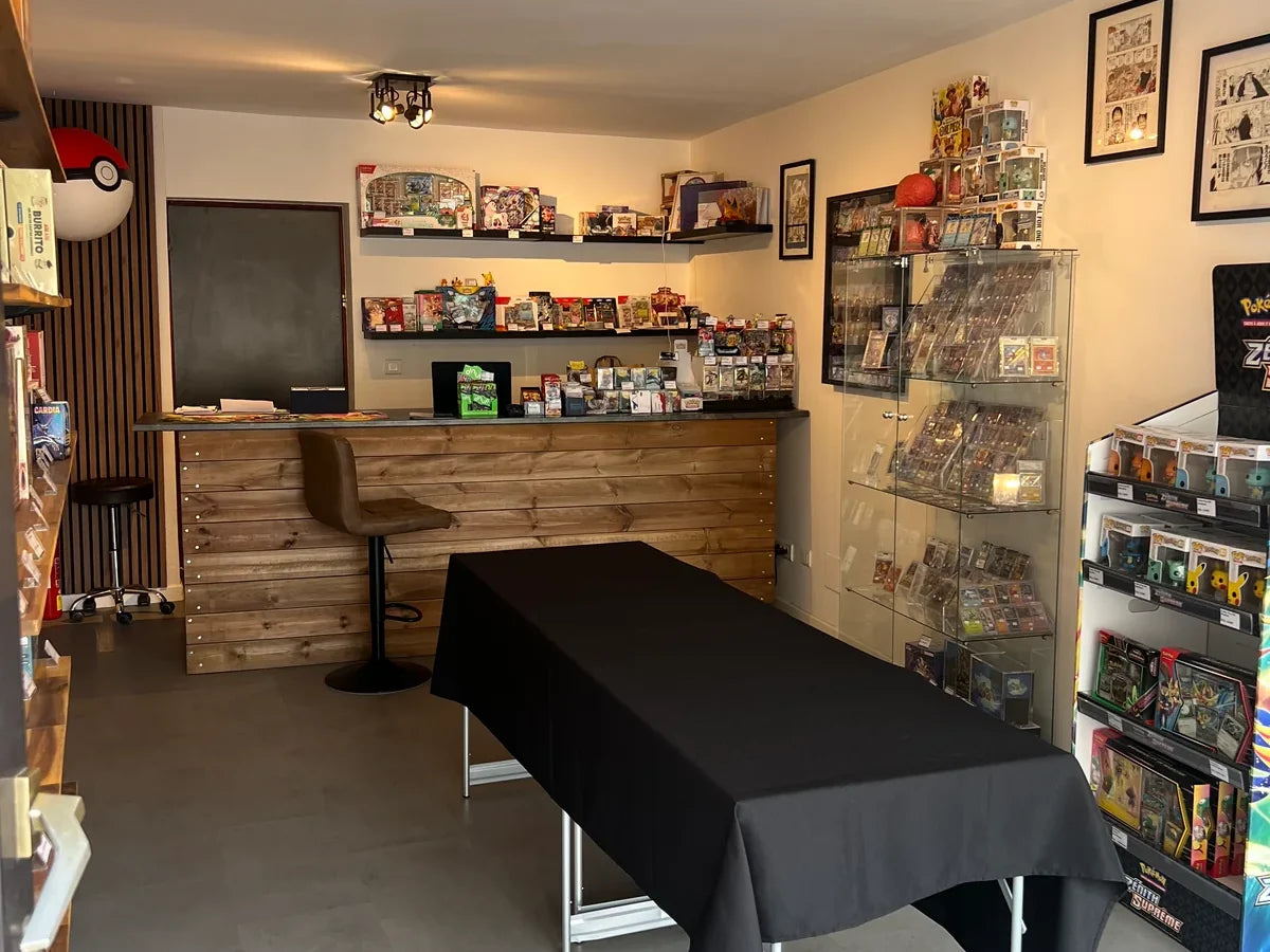 Inside the Cards Game Collect shop: wooden counter, shelves of Pokémon boxes, card display case and figure stand